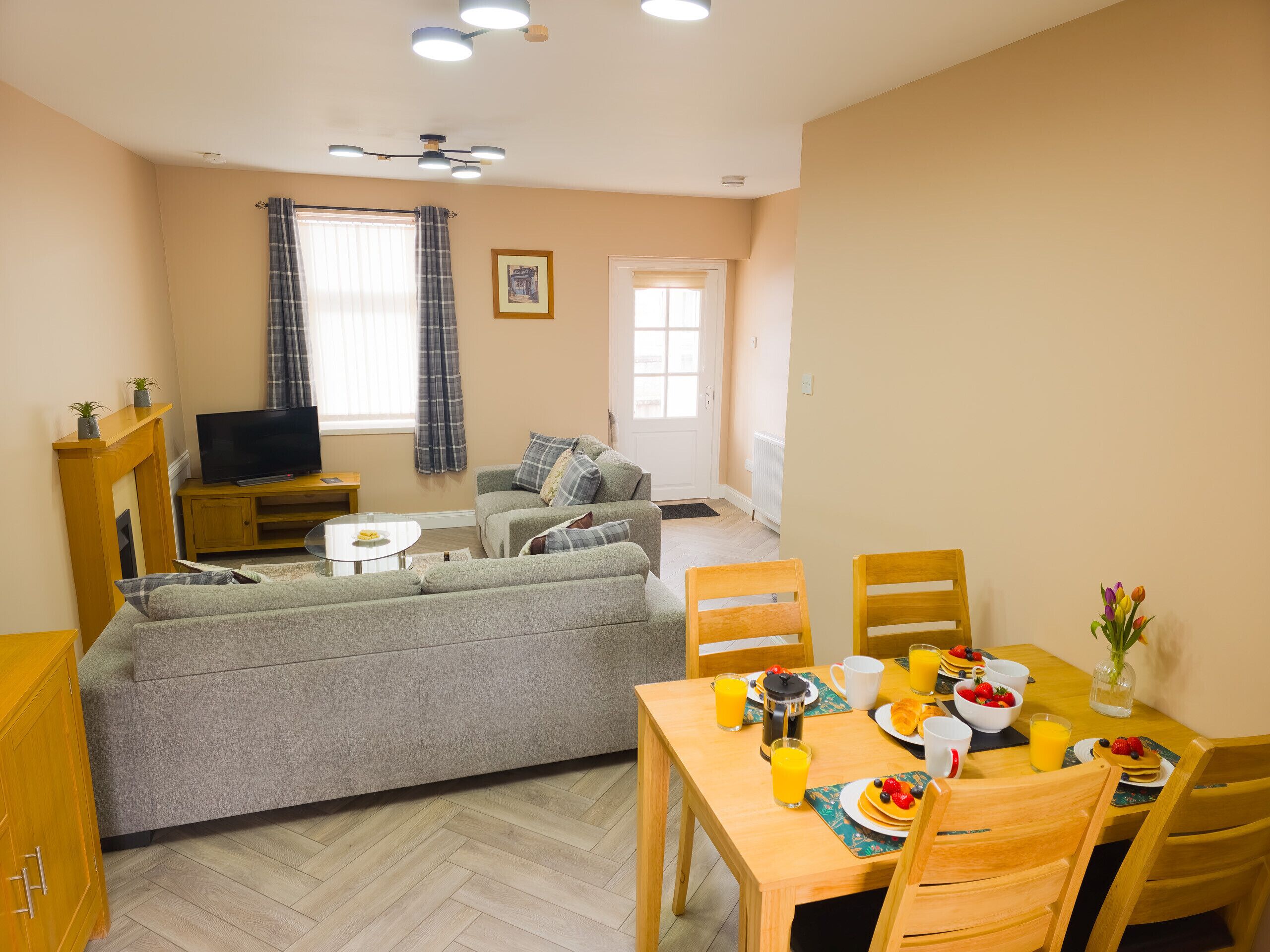 Ein Wohnzimmer mit Sofa, Fernseher und Essbereich, gedeckt für ein Frühstück.