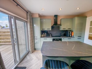 Una cocina moderna con una isla grande, puertas correderas de vidrio y vistas al exterior.