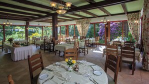 Ein Restaurant mit gedeckten Tischen, Holzstühlen und Blick auf den Garten.