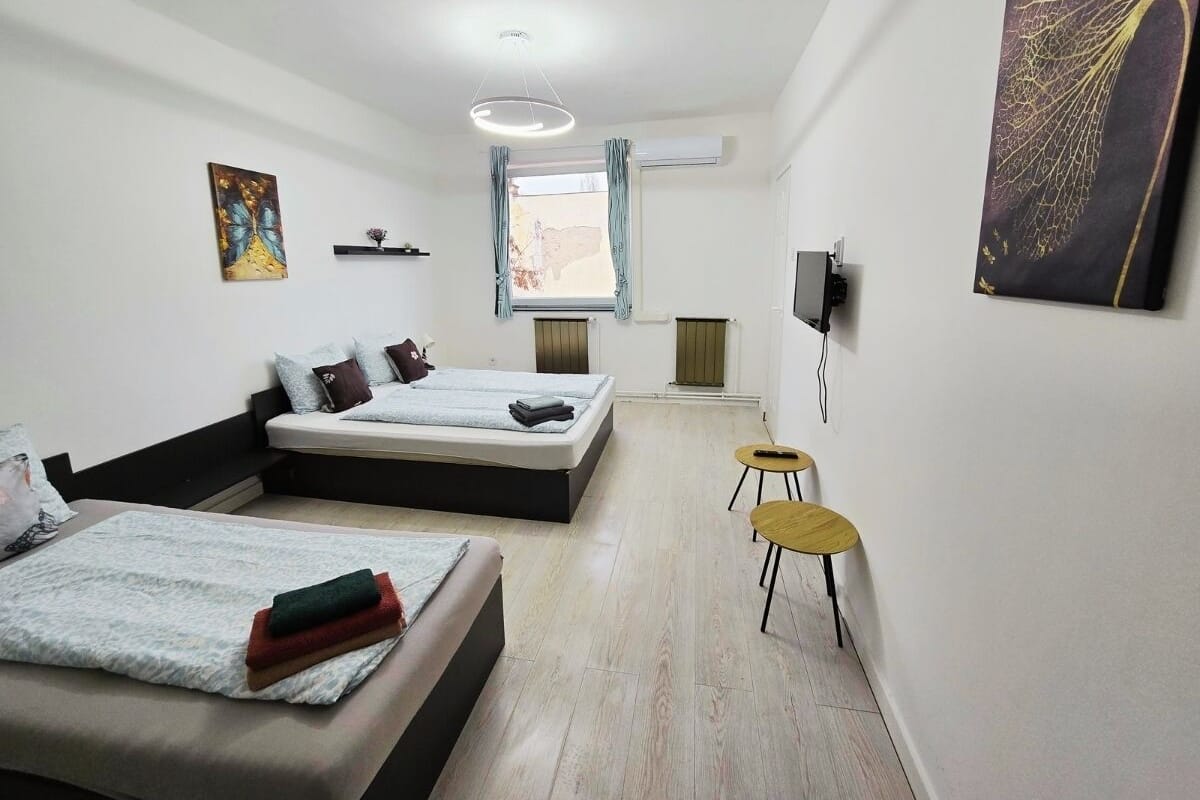 A modern hotel room with a large bed, a smaller bed, a desk, and a chair.