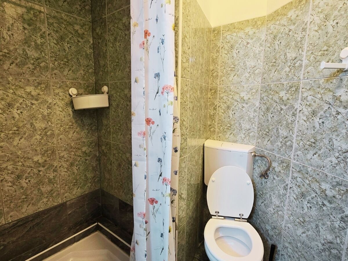 A bathroom with a shower, toilet, and marble walls.