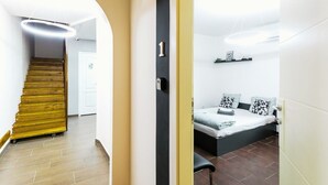 Un interior moderno con una escalera, una cama con cabecera y una lámpara fijada a la pared.