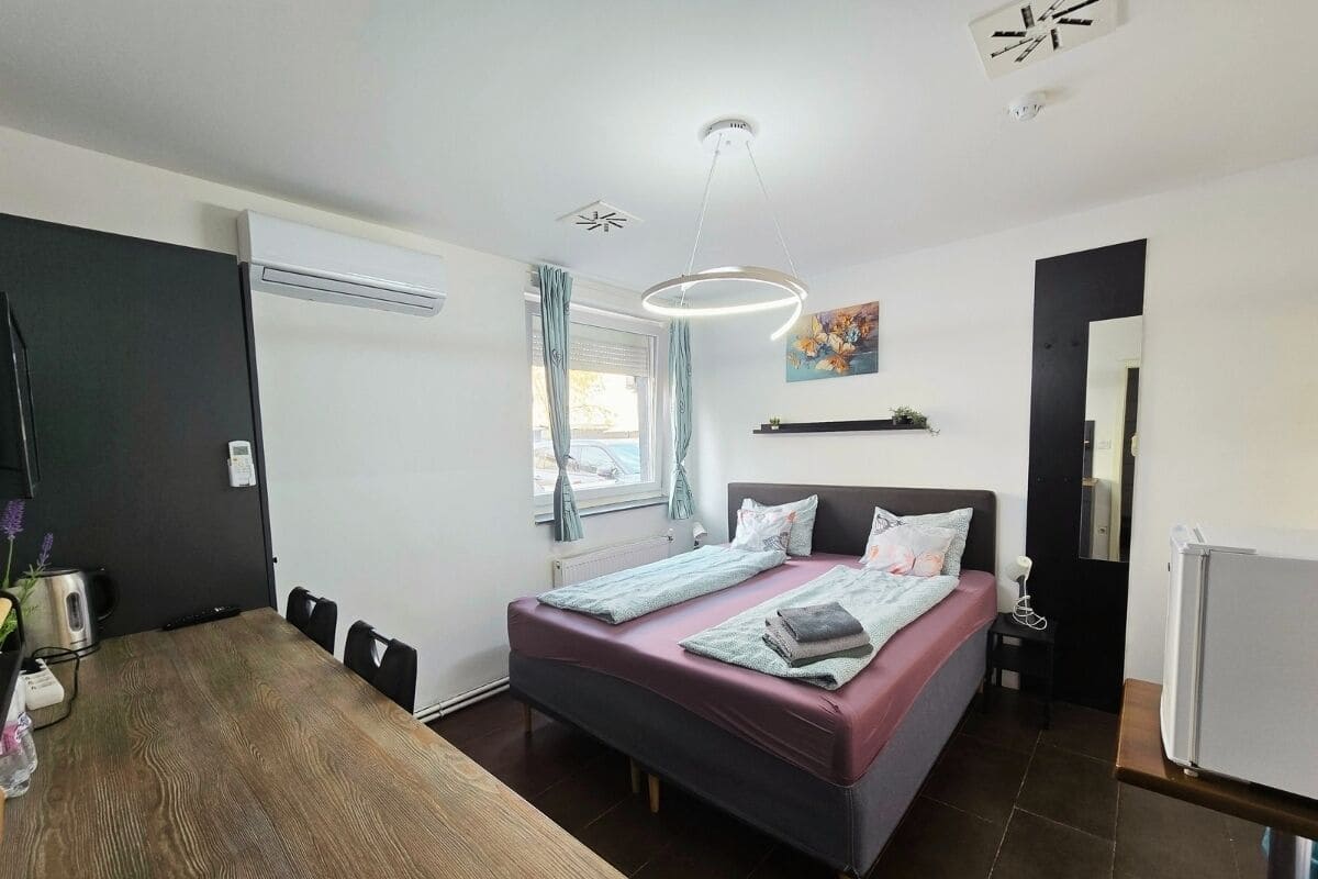 A modern bedroom with a bed, bedside table, and a desk area.