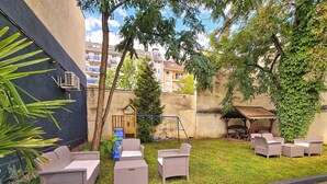 Un patio con muebles de mimbre, un columpio y una casita de juegos.