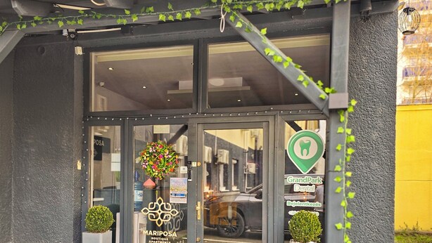 Entrada de un hotel boutique con puerta de cristal, felpudo y un cartel de GrandPark Dental.