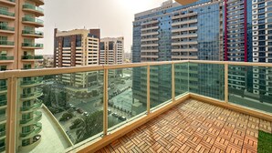 A balcony with a view of surrounding high-rise buildings and a parking area below. - 2 Bedroom APT in Elite Sports Residence  (Dubai)