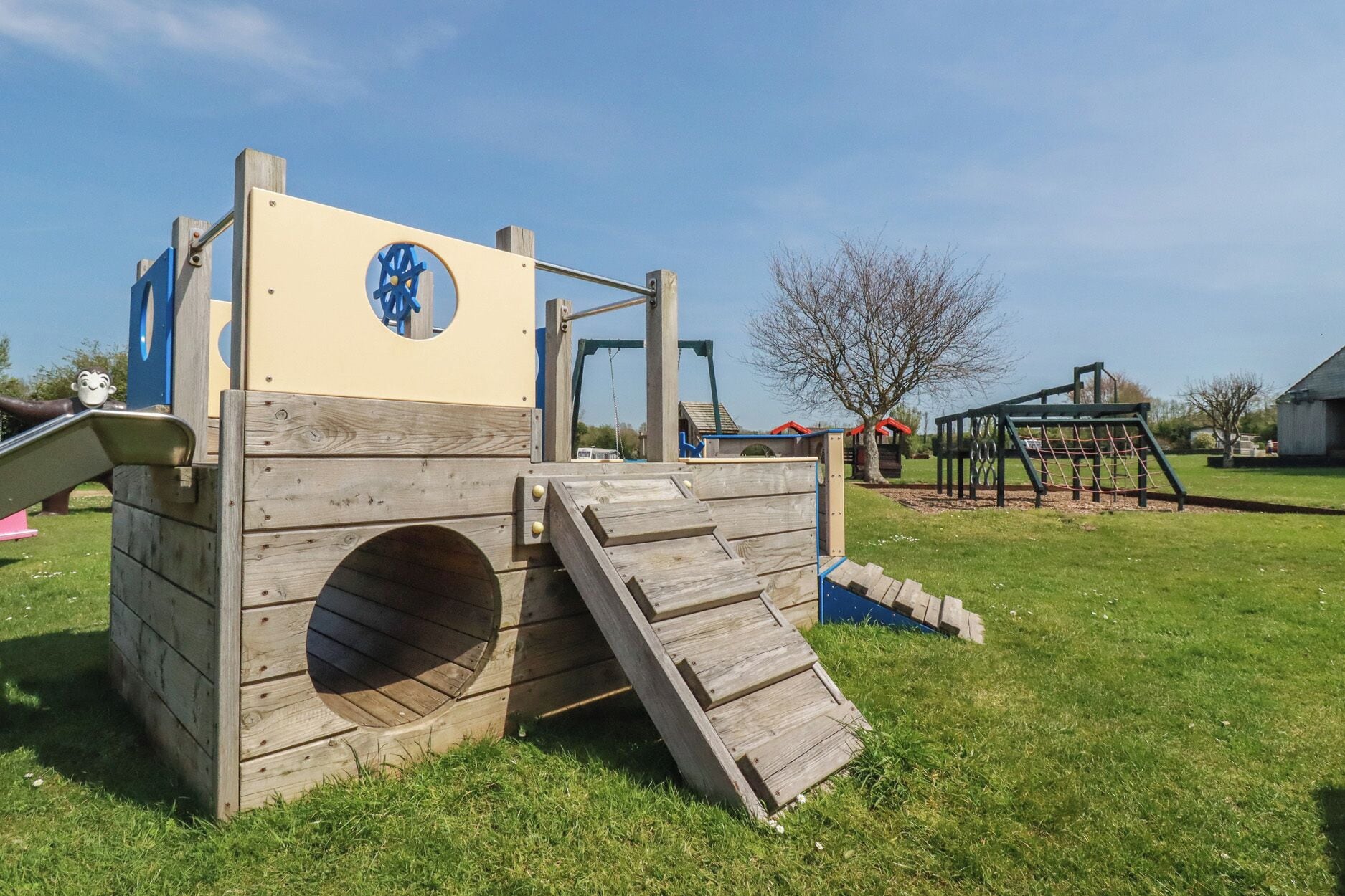 Une structure de jeu en bois avec un toboggan et un mur d’escalade.