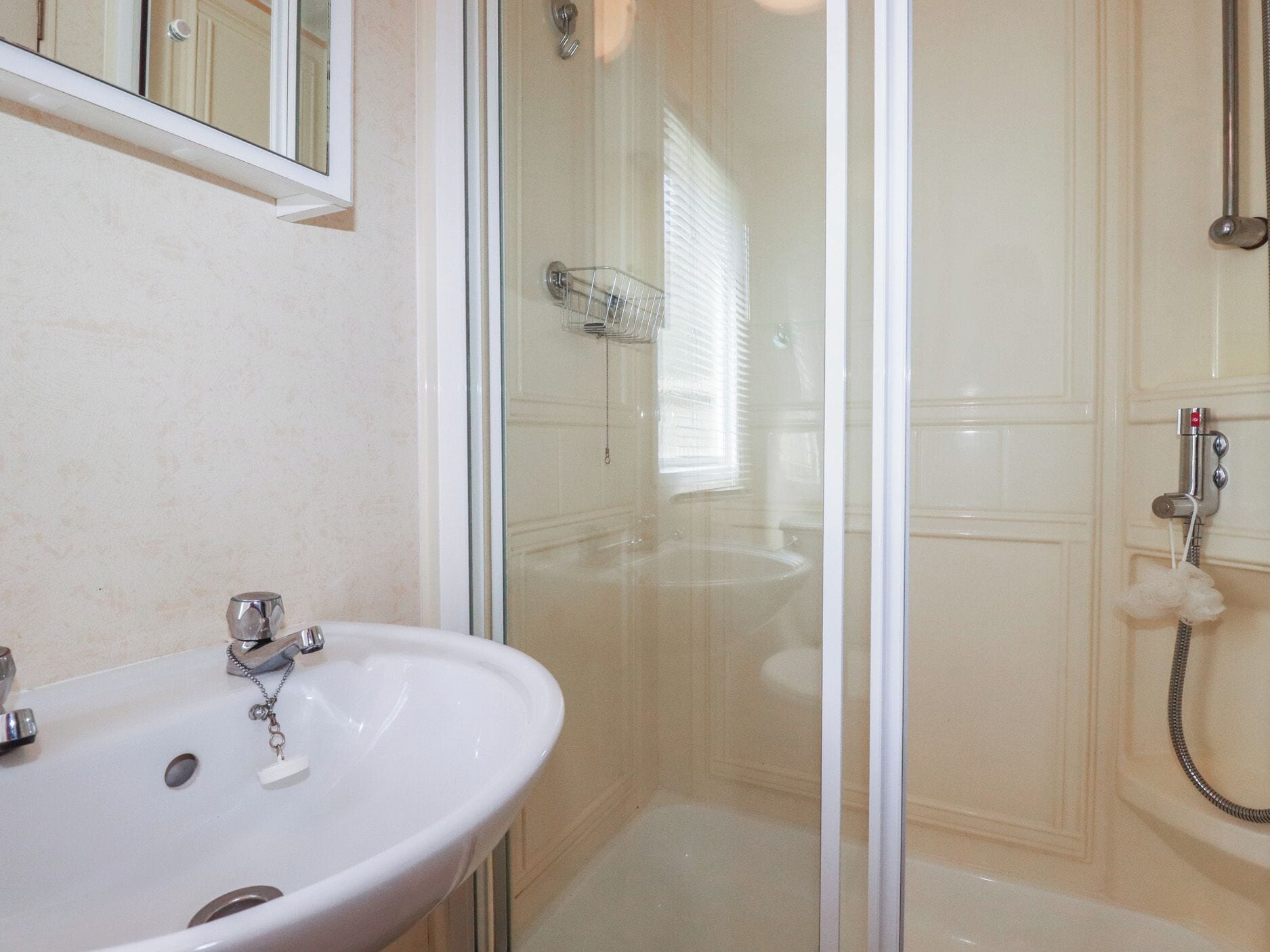 A bathroom with a white sink, a glass shower enclosure, and a bathtub.