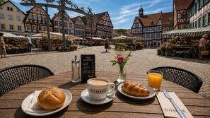 Uma mesa com um croissant, café e suco em um mercado europeu.