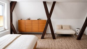 Une chambre à coucher comprenant un lit, une commode en bois, une chaise et une grande structure en bois en forme de X.
