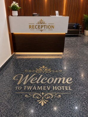 A reception desk with a 'RECEPTION' sign and a 'Welcome to Twamev Hotel' welcome mat. - Jeet residency by twamev (New Delhi)