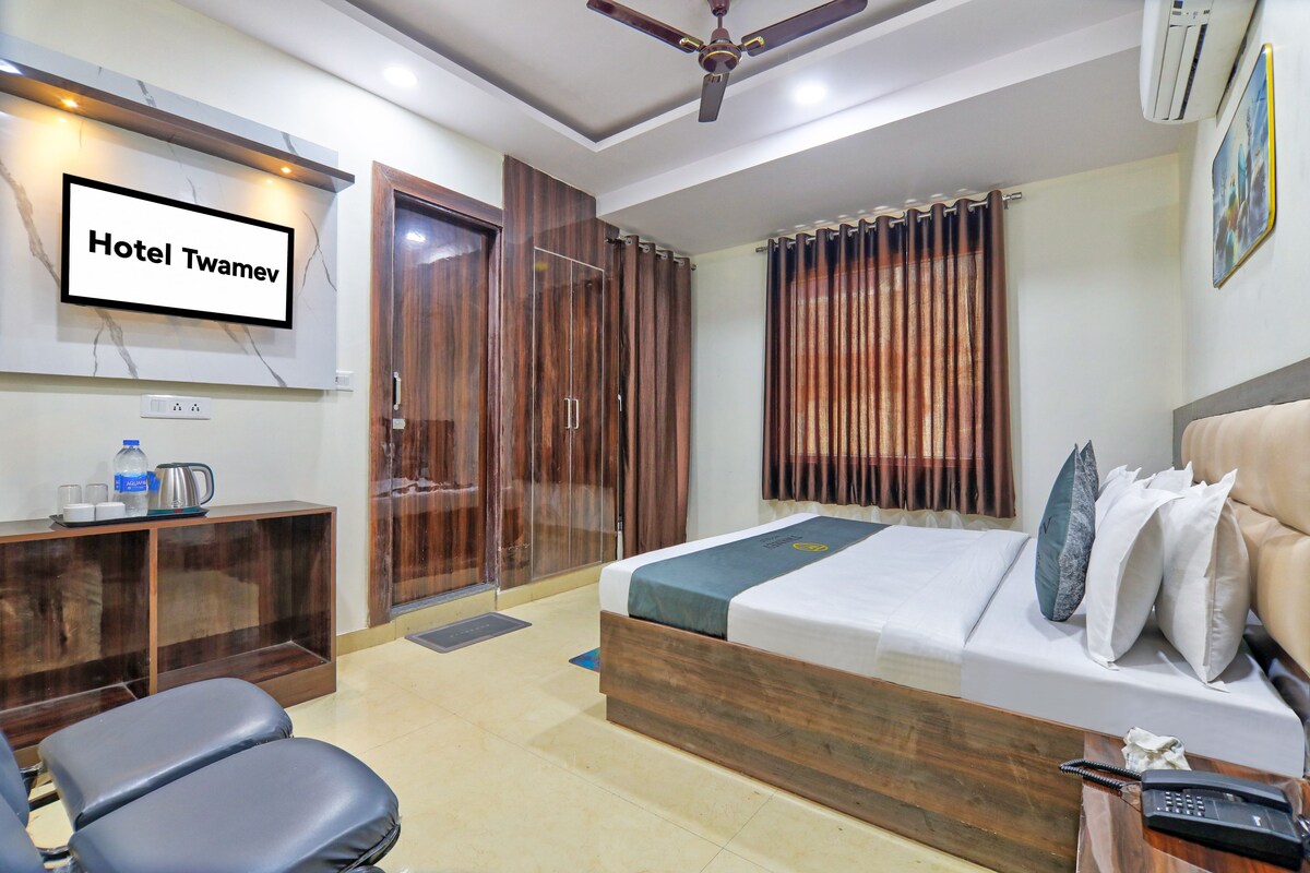 A hotel room with a bed, a desk, a chair, a wardrobe, and a television.