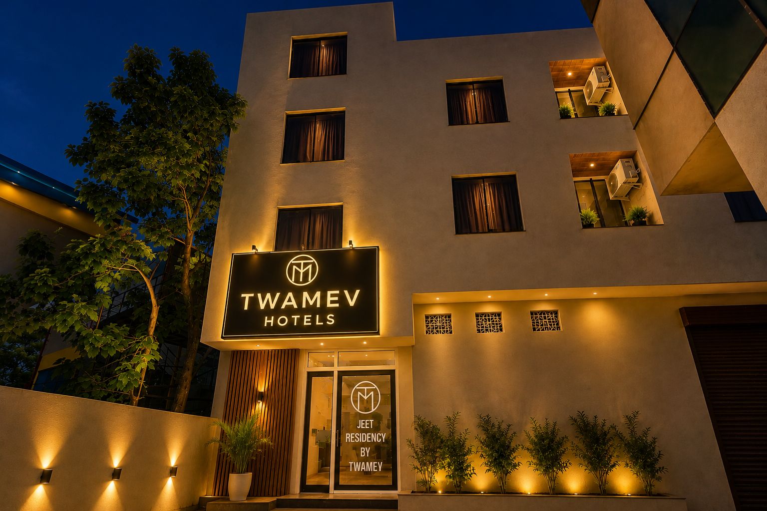 Facciata di un hotel con un cartello che riporta 'TWAMEV HOTELS' e 'JEET RESIDENCY BY TWAMEV'.