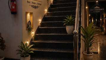 Een trap met een bordje voor Jeet Residency by Twamev, omringd door potplanten en decoratieve verlichting.