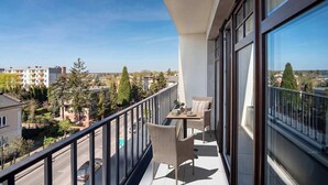 A balcony with wicker furniture, a view of the city, and a clear sky.