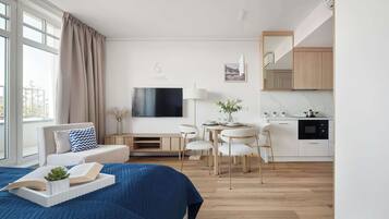 Una habitación de hotel moderna con cama, televisor, zona de comedor y cocina.