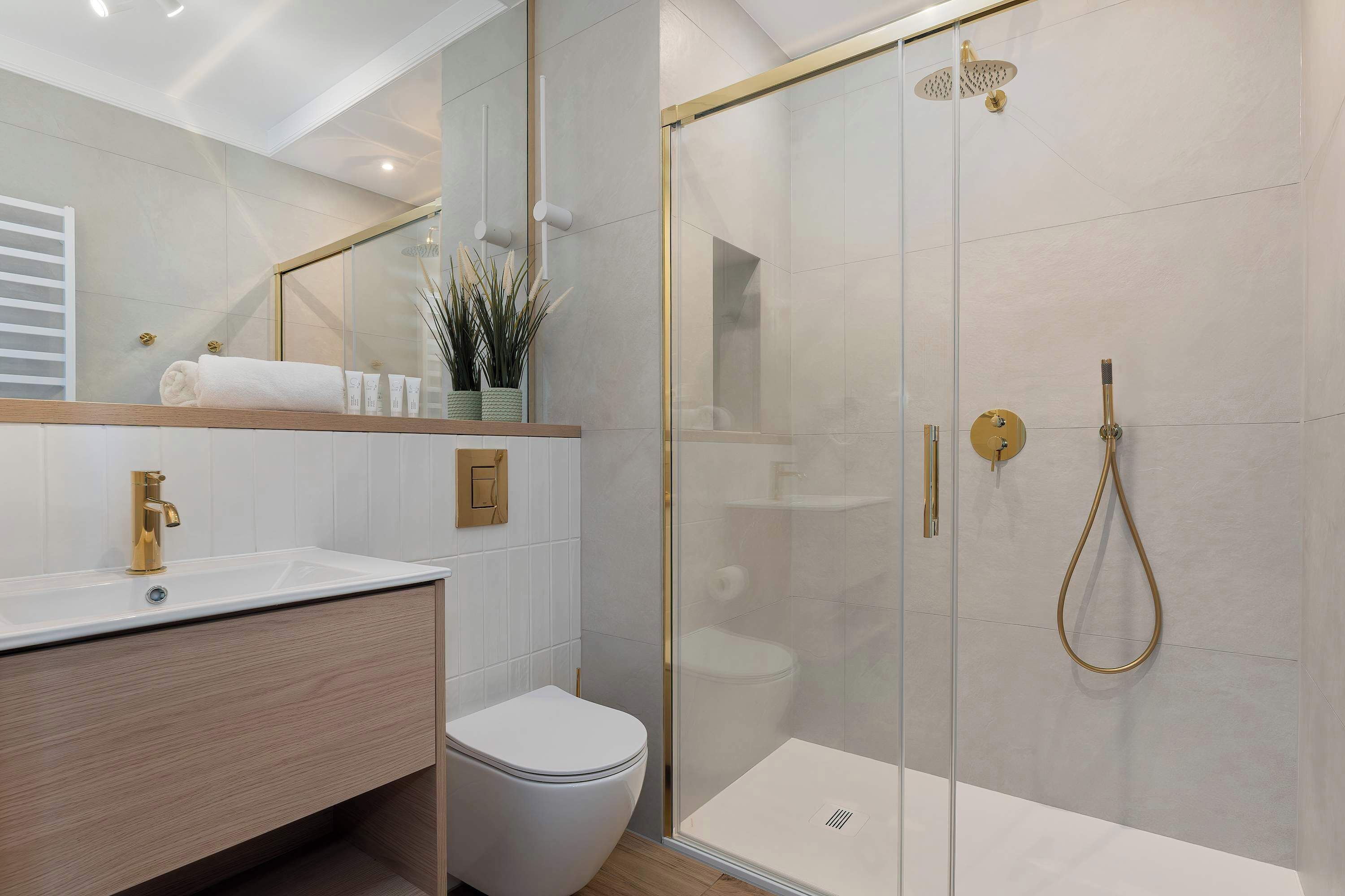 Ein modernes Badezimmer mit einer gläsernen Duschkabine, einer weißen Toilette und einem hölzernen Waschtisch.