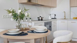 A modern kitchen with white cabinets, a round dining table, and a vase with flowers.