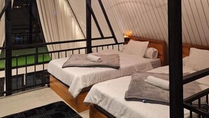 A cozy attic bedroom with a sloped ceiling, wooden beams, and a large window. - Villa Dieng Mezzaluna (Kejajar)