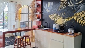 A modern kitchen with a black wall mural, a wooden bar counter, and a view of the outdoors. - Villa Dieng Mezzaluna (Kejajar)