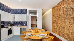 Een moderne keuken met een eetgedeelte, met een ronde houten tafel met stoelen, een inbouwoven en een magnetron.