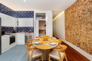 Eine moderne Küche mit Essbereich, ausgestattet mit einem runden Holztisch, Stühlen, einem Einbauofen und einer Mikrowelle.