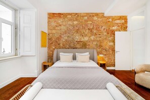 Ein Schlafzimmer mit Bett, Kopfstütze, Nachttisch, Stuhl und einer Wand mit strukturierter Oberfläche.