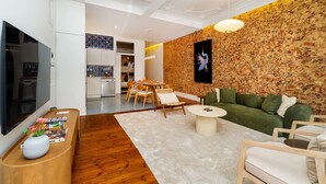 Een moderne woonkamer met een flatscreen televisie, een eethoek en een keuken.