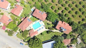 Vista aérea de un vecindario con varias casas, una piscina y paneles solares en los tejados.