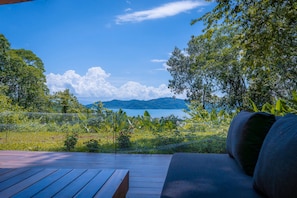 A wooden deck with a sofa and a view of a lake and mountains.