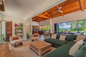 A spacious living area with a wooden ceiling, a green sofa, a wooden coffee table, and a bookshelf.