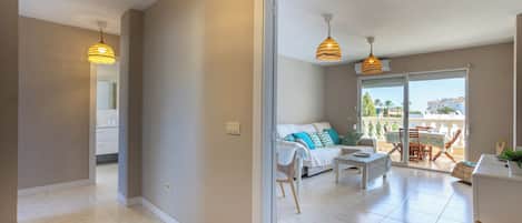 A modern apartment with a living area, dining space, and a balcony with a view.