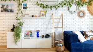 A room with a white brick wall, a blue sofa, a white cabinet, and a ladder. - HAPPYFEW SUITE FABRON (Nice)