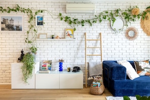 A room with a white brick wall, a blue sofa, a white cabinet, and a ladder. - HAPPYFEW SUITE FABRON (Nice)