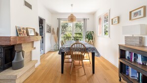 A dining area with a table, chairs, a hanging light fixture, and a bookshelf. - Happyfew Villa Monica (Nice)