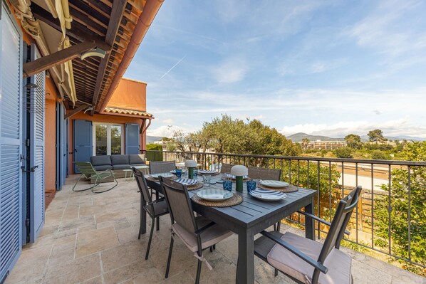Un patio con mesa lista para comer, asientos al aire libre y vistas del paisaje.