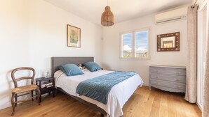 A bedroom with a bed, a chair, a dresser, a mirror, and a window. - Happyfew Villa Monica (Nice)