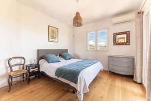 Un dormitorio con cama, una silla, cómoda, espejo y ventana.