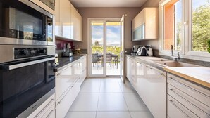 A modern kitchen with a sliding glass door leading to an outdoor patio. - Happyfew Villa Monica (Nice)