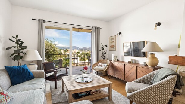 A living room with a sofa, armchair, coffee table, and a view through a sliding door to an outdoor area. - Happyfew Villa Monica (Nice)
