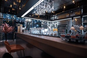 Un espace bar doté d’un long comptoir, de nombreux verres et d’un luminaire suspendu.