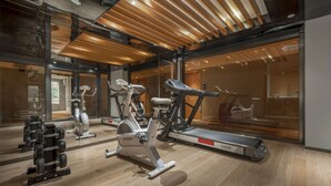 Un gimnasio con equipo de ejercicio, cinta de correr y pared espejada.