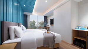 Habitación de hotel moderna con una cama grande, un escritorio, un televisor y vistas al exterior.