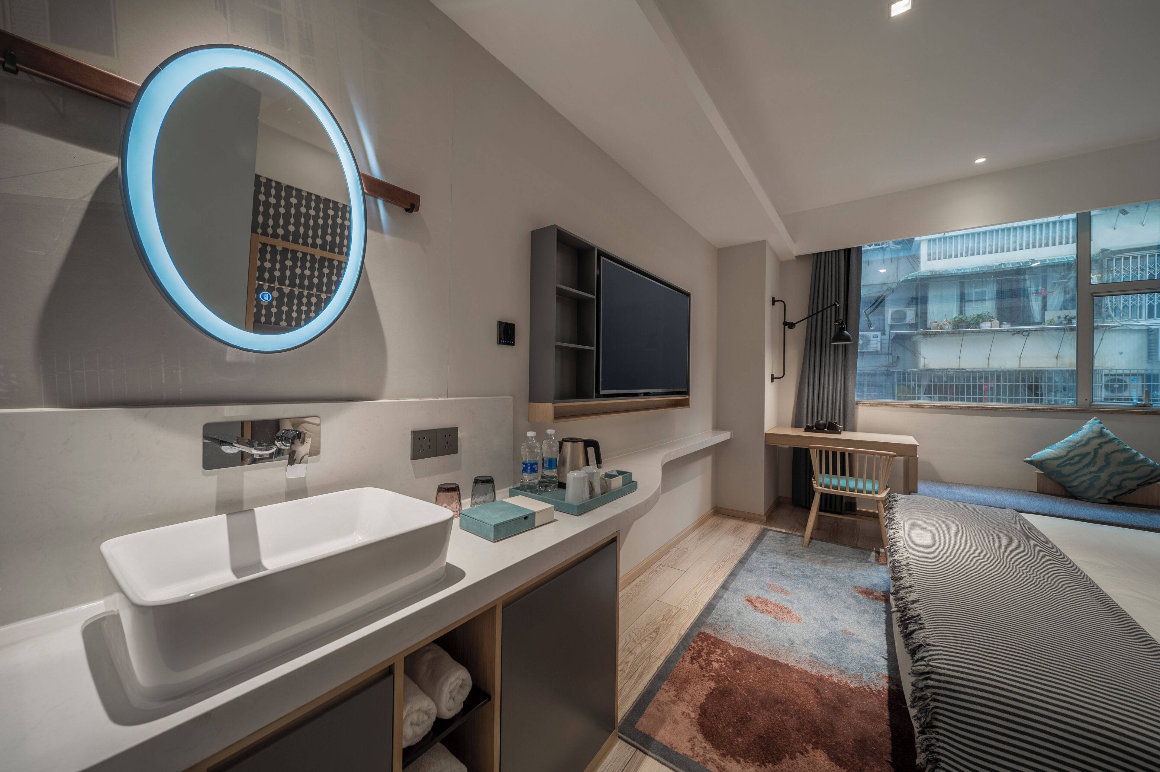 Un baño moderno con un lavamanos grande, un espejo y televisor integrado.