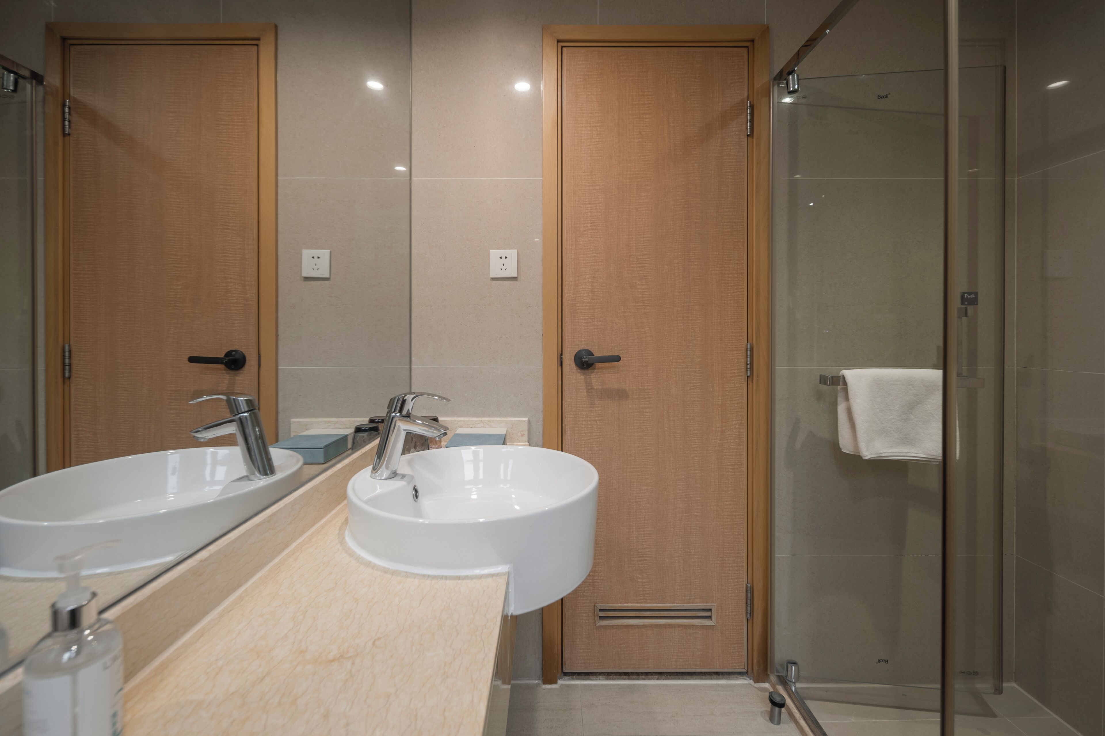 Un baño con dos lavamanos, un espejo y cabina de ducha con paredes de vidrio.