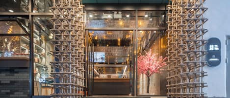 A hotel entrance with a staircase, a reception desk, and a decorative cherry blossom tree.