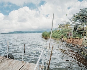 A wooden dock extending into calm water with a distant shoreline and overcast sky. - Catur Glamping Bedugul (Baturiti)