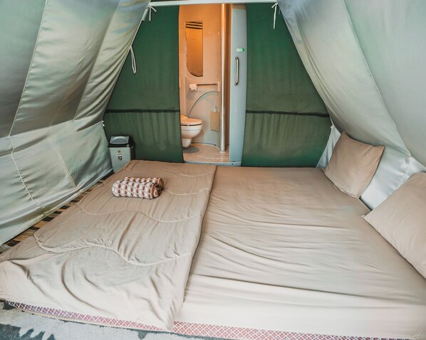 Une tente équipée d’un lit, de toilettes et d’une petite table.