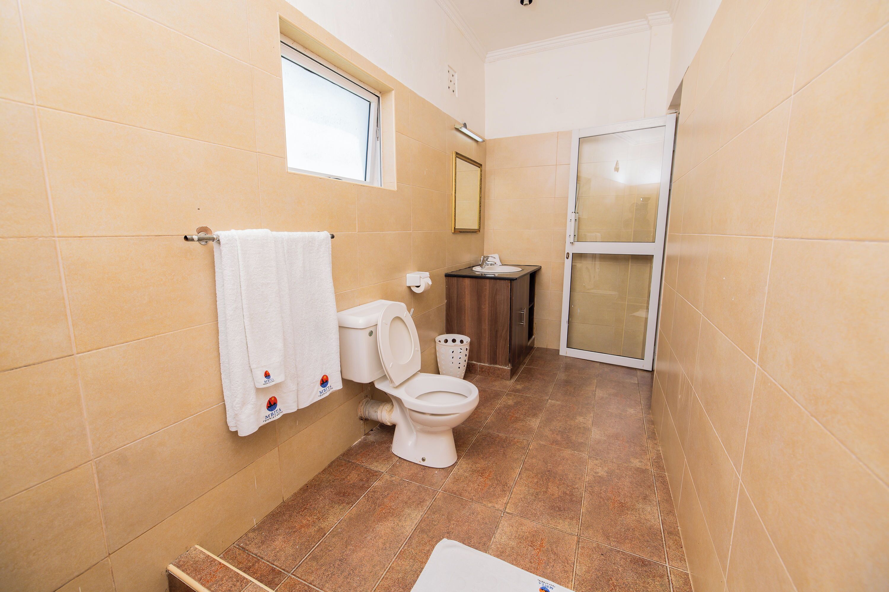 A bathroom with a toilet, sink, and window.