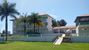 Un hotel de varios pisos con una escalera central, un espacio exterior cubierto y un césped bien cuidado.